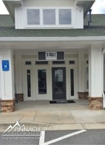 Business signage for a storefront designed by Pinnacle Custom Signs. The image shows a professional, sleek sign above the entrance displaying 'SNIGLE' along with a branded door mat, enhancing the business’s professional appearance and brand visibility.