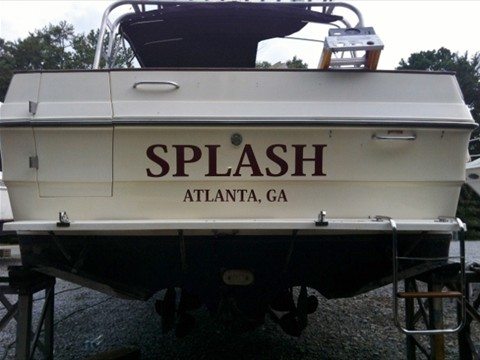 A boat on a trailer with the stern facing the camera, displaying the custom wrap text 'SPLASH' in bold, maroon letters, and 'ATLANTA, GA' underneath. The boat is set against an outdoor background, highlighting the professional application of the boat wrap by Pinnacle Custom Signs.