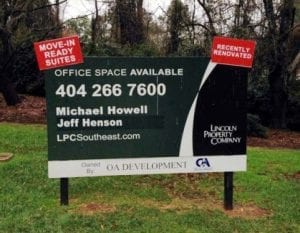 A commercial property signage displayed on a grassy area with trees in the background. The sign reads 'Office Space Available' with contact information for Michael Howell and Jeff Henson, along with their phone number, and website. The sign features the Lincoln Property Company logo and the text 'Move-In Ready Suites' and 'Recently Renovated' in red banners at the top corners. At the bottom, it indicates 'Owned by OA Development' with the associated logo.