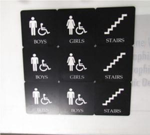 Set of black and white lobby signs designed by Pinnacle Custom Signs, indicating boys' and girls' restrooms, accessibility, and stairs. Each sign features clear, universally recognizable icons to provide easy navigation and enhance the functionality of the lobby area.