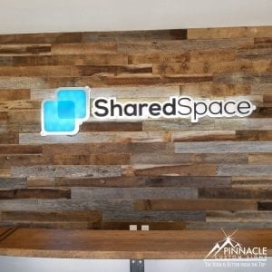 using a wood panel backdrop, this lobby sign uses frosted acrylic, brushed metal, and vinyl lettering