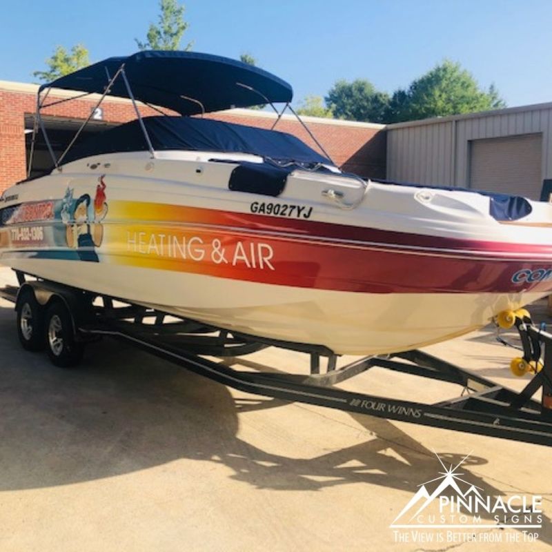 A boat with a vibrant wrap advertising heating and air services, showcasing a colorful gradient design. This custom boat wrap was created by Pinnacle Custom Signs, demonstrating their expertise in producing high-quality, eye-catching graphics for various applications.