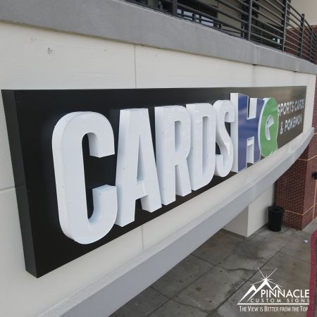 Exterior building sign for Cards HQ, featuring illuminated letters for 'Cards' and 'HQ' with the tagline 'Sports Cards & Pokémon,' created by Pinnacle Custom Signs.